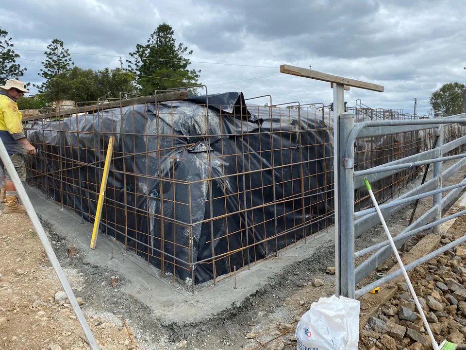 Reinforcement and formwork beside a metal fence.