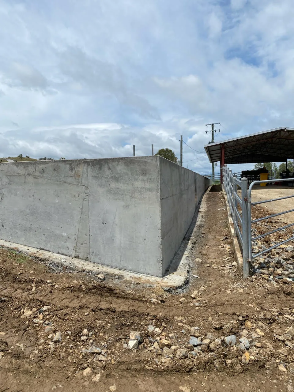 Concrete wall and adjoining ground near a farm structure.