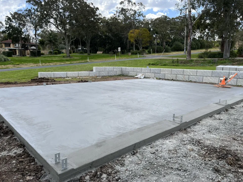 Concrete slab with fencing and trees in the background.