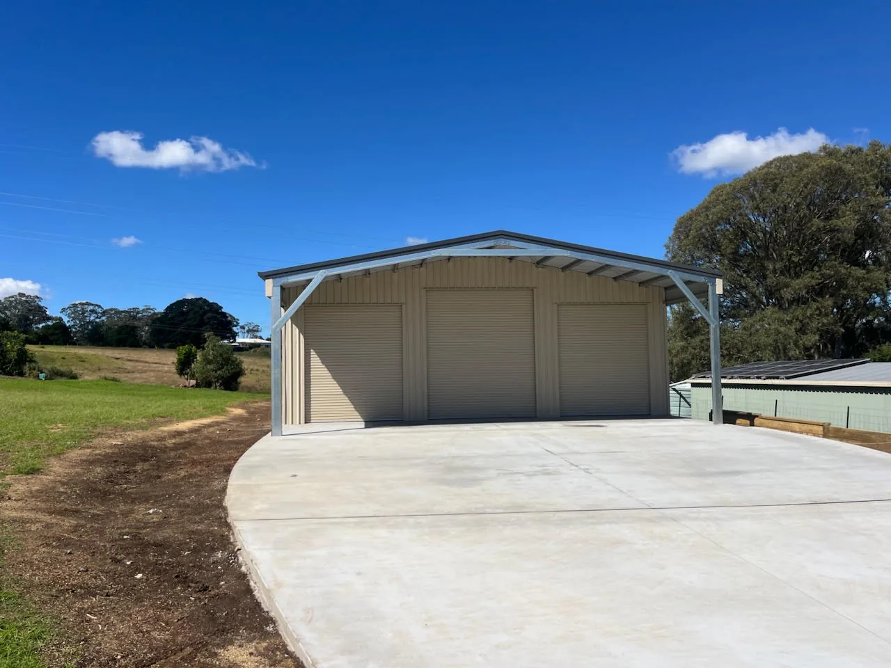 Concrete apron in front of a three-door shed.